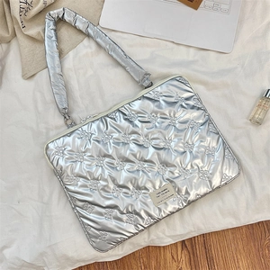Close-up of silver quilted laptop sleeve with embossed bow patterns and zipper detail