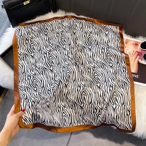 Détail d'un foulard en soie à rayures zébrées avec bordure en satin marron sur fourrure