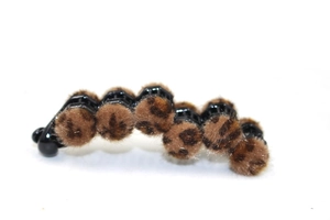 Detail of black vertical hair clip featuring plush leopard print pom-poms and pearls