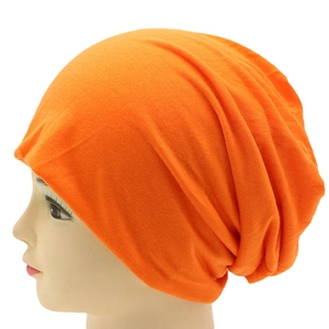 Detailed close-up showing the soft knitted texture of a bright orange slouchy beanie hat