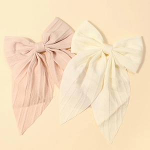 Detail view of pink and beige fabric bow hair clips with elegant long ribbon tails