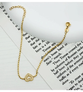 Detail of 18K gold heart bracelet with white zircon inlay on an elegant book background