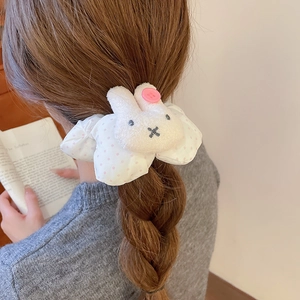 Detail view of a plush white bunny and pink polka dot bow hair scrunchie on a ponytail