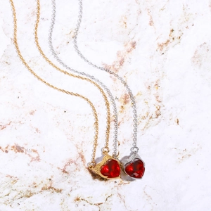Gold and silver stainless steel heart pendant necklaces with red zircon wings on marble