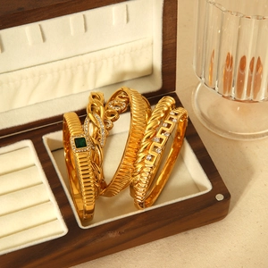 Détail de quatre bracelets vintage dorés avec pierres d'émeraude et cristaux fins