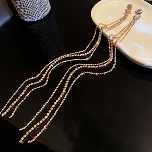 Macro shot of long golden tassel earrings with multi-colored AB crystals and drop stone