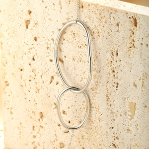 Detail of interlocking irregular oval rings on a minimalist silver chain necklace
