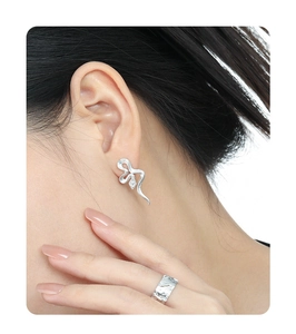 Close-up of S925 silver snake skin textured earrings and wide band ring worn by model