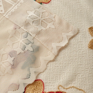 Macro shot of gold embroidery on beige lace curtain with floral patterns and scalloped edge