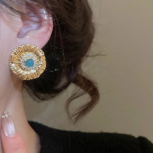 Close-up of vintage flower earrings with blue cat-eye stone and champagne gold finish