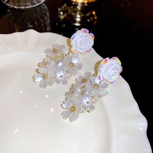 Detailed close-up of acrylic flower tassel earrings with pearlescent finish on a ceramic plate