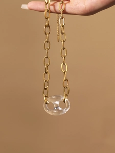 Gedetailleerde close-up van gouden ketting met transparante hars varkensneus schakelhanger