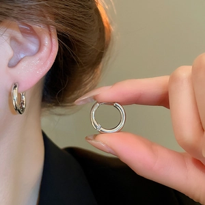 Close-up detail of silver hoop earrings showing smooth polished finish on model's ear