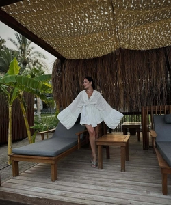 Détail d'une robe de vacances bohème blanche avec larges manches cloche et tissu texturé