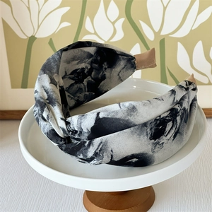 Detail of cross knot headband with black and white ink marble pattern on a display stand