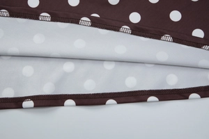Vue détaillée du tissu à pois marron et des coutures de précision d'une robe ajustée