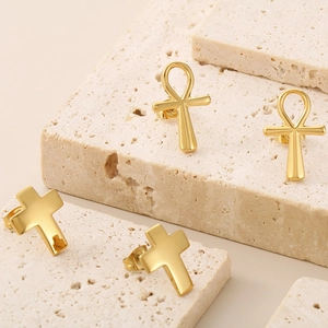 Detailed close-up of 18K gold-plated stainless steel Ankh and cross stud earrings