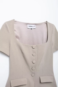 Detail of beige square neck top showing buttons and decorative pocket flaps