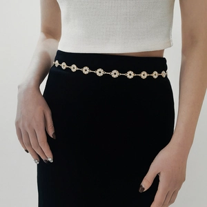 Detailed view of a gold rhinestone metal waist chain with circular accents on a black dress