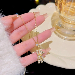 Detailed view of the sparkling gold bear and star pendant necklace held by fingers