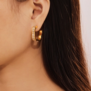 Gold plated stainless steel wave earrings with zircon stones worn by a female model