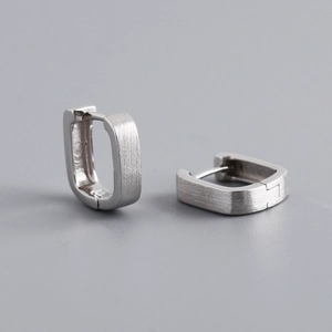 Macro detail of silver square hoop earrings with a modern brushed matte metal texture