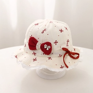 Close-up of baby sun hat featuring red bow prints and delicate white lace edges