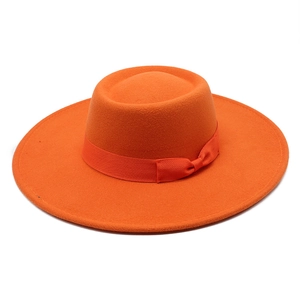 Détail d'un chapeau en feutre orange vif orné d'un ruban gros-grain assorti