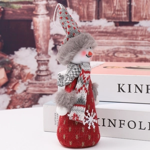 Close-up of red knit snowman ornament with gold heart pattern on white books