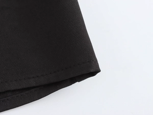 Vue détaillée de l'ourlet de la robe noire montrant une couture professionnelle à double aiguille