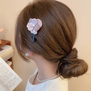 Détail de la pince à cheveux fleur en résine rose avec perles sur le modèle