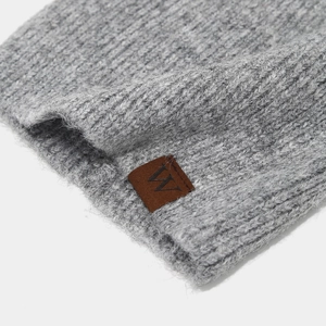 Close-up of grey ribbed knit beanie showing thick wool texture and brown leather 'W' patch
