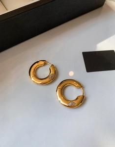 Macro detail of gold chunky hoop earrings with water drop cubic zirconia inlay