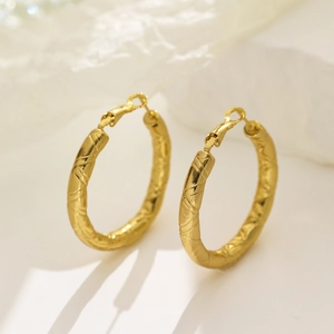 Polished gold hollow hoop earrings with intricate textured pattern and secure clasp