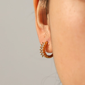 Élégantes boucles d'oreilles créoles en acier titane doré avec zircons sur modèle