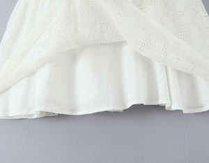 Close-up of delicate floral lace outer layer and soft cotton lining on white mini dress
