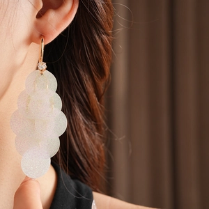 Macro view of C-shape fringe earrings with shimmering sequins and gold studs