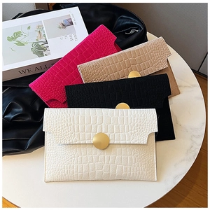Detail showing crocodile-embossed faux leather texture and gold magnetic snaps on envelope bags