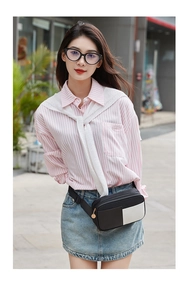 Close-up of a stylish black and white contrast waist bag on a pink striped shirt