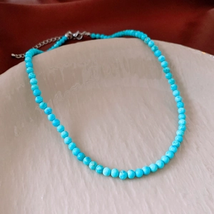Gros plan du collier en perles de turquoise avec textures minérales et fermoir mousqueton argenté