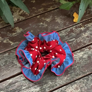 Dettaglio scrunchie con pois rossi e bordo a balze in denim blu su legno