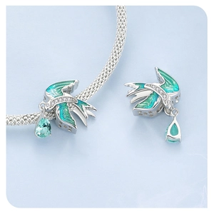 Macro view of 925 silver bird charm with blue enamel and pear-cut crystal pendant