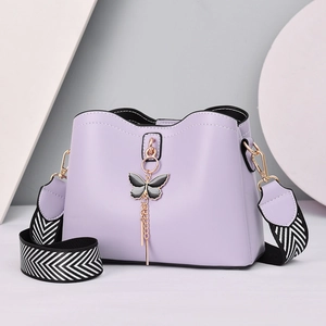 Minimalist purple bucket bag with golden butterfly charm and woven chevron strap