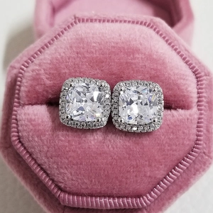 Macro view of cushion cut halo stud earrings presented in a pink velvet jewelry box