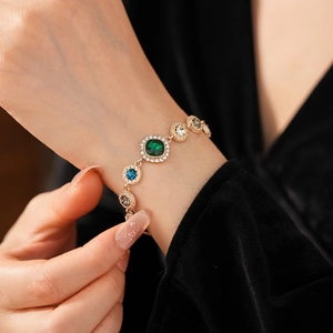 Detailed close-up of a vintage gold bracelet with emerald and sapphire zircon stones
