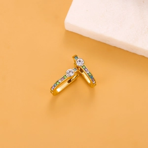 Detailed macro shot of golden earrings with multicolor zircons on orange backdrop
