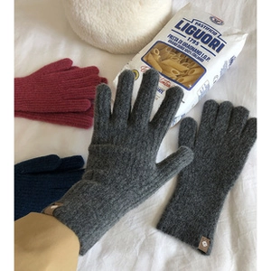 Primer plano de guantes de lana tejidos táctiles en gris oscuro sobre una sábana blanca
