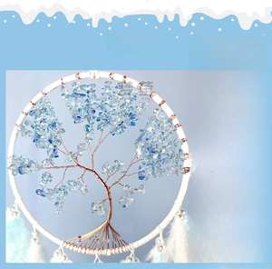 Detail of tree of life dreamcatcher featuring light blue crystals and soft feathers