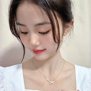 Elegant gold flower necklace with white petals and green leaves on a female model