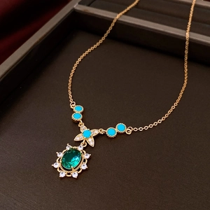 Detailed macro of vintage gold necklace with green gemstone pendant and blue beads